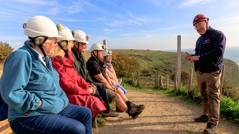 An image of visitors to Fan Bay Deep Shelter being briefed by their guide prior to descending into the tunnels on a sunny day
